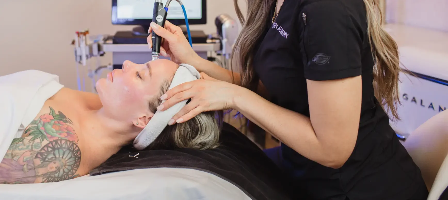 Practitioner using a handheld device on a patient’s forehead while the patient lies on a treatment bed