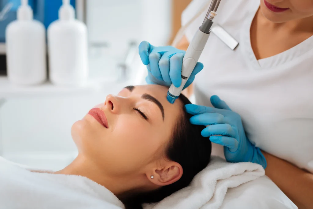 Practitioner performing a HydraFacial treatment on a client's forehead with a handheld device