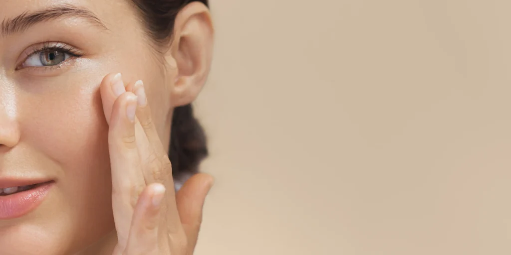 Close-up of a person touching the cheek of smooth, glowing facial skin